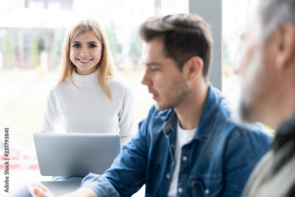 Sharing opinions. Group of young modern people in smart casual wear discussing business while working in the creative office. Sharing opinions. Group of young modern people in smart casual wear discussing business while working in the creative office.