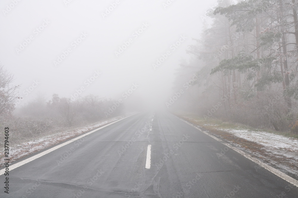 Straight empty wet asphalt road during foggy conditions Straight empty wet asphalt road during foggy conditions