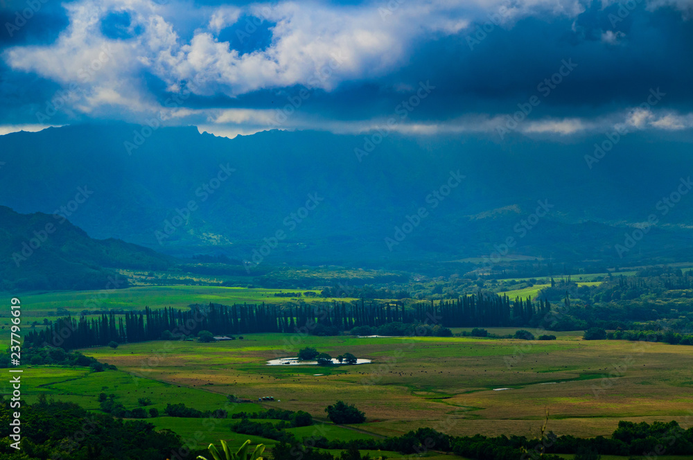 Obraz premium Aerial view overlooking a tropical valley with the sun streaking through the clouds on the island of Kauai, Hawaii, USA