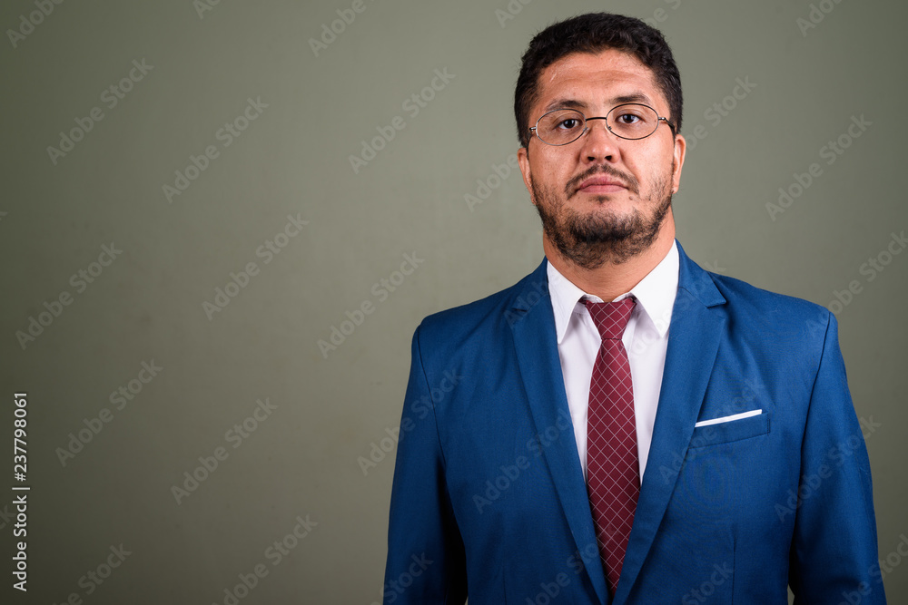 Bearded Persian businessman wearing suit against colored backgro