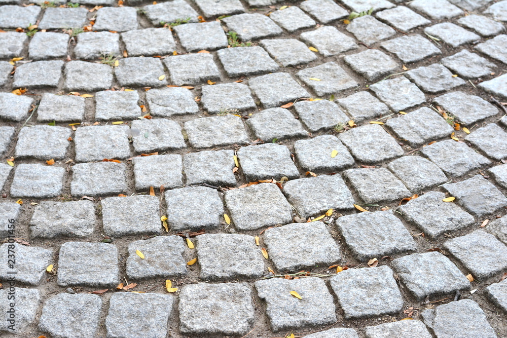 Close up outdoor view of the surface of a paved road. Pattern of grey granit cobblestones. Mosaic and geometric design. Abstract image with repetitive shapes and lines. Close up outdoor view of the surface of a paved road. Pattern of grey granit cobblestones. Mosaic and geometric design. Abstract image with repetitive shapes and lines.