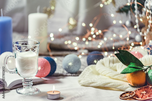 Romantic winter and New Year's style interior view with a candle, book, garland and glass of milk