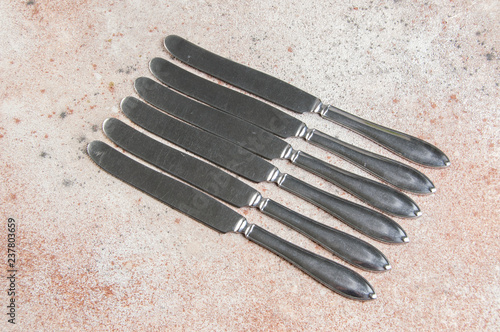 Six vintage silver knifes on concrete background photo