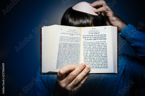 Jewish male wearing Kippah praying reading Bi-lingual Hebrew French mahzor prayer book from 1920 used on the High Holy Days of Rosh Hashanah and Yom Kippur - blue vignette. photo