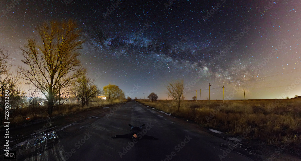 Traveller lying down the stars. Caucasian guy travels under the stars. The guy lying below the night starry sky. Watching milky way.