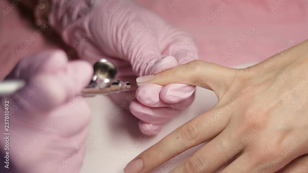Master makes manicure with airbrush in white Master makes manicure with airbrush in white