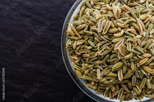 Essential oil of fennel seeds on a dark stone background