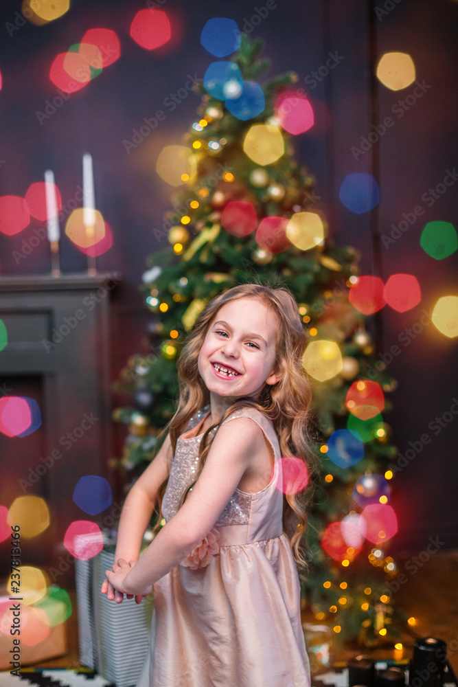 Little girl under the Christmas tree. A girl with gifts under the tree in anticipation of magic Little girl under the Christmas tree. A girl with gifts under the tree in anticipation of magic