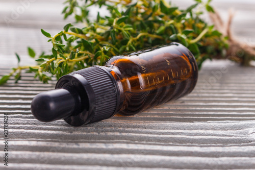 essential oil of thyme on a gray wooden rustic background