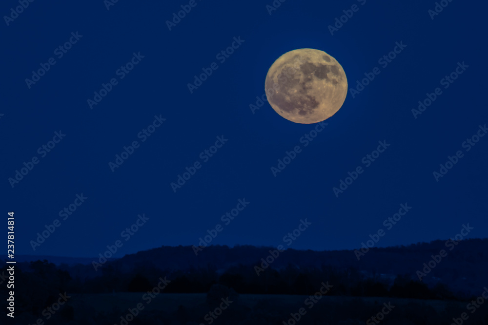 Full Moon over rolling hills silhouette with blue sky