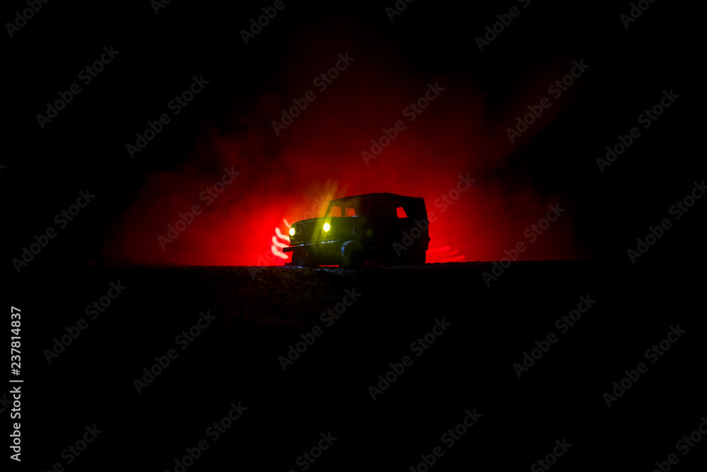Off roader jeep silhouette on dark toned foggy sky background. Car with light at night. Off roader jeep silhouette on dark toned foggy sky background. Car with light at night.