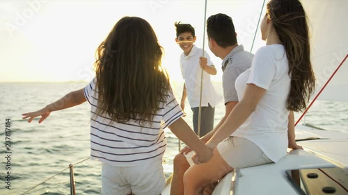 Young ethnic Latino family on vacation enjoying carefree lifestyle sailing the ocean on luxury yacht sun flare  photo