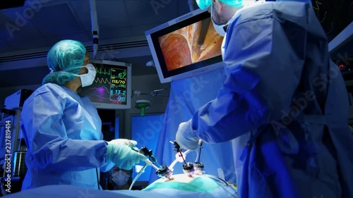 European Medical surgeons training by performing laparoscopic surgery on the patient in operating theatre using video camera technology  photo