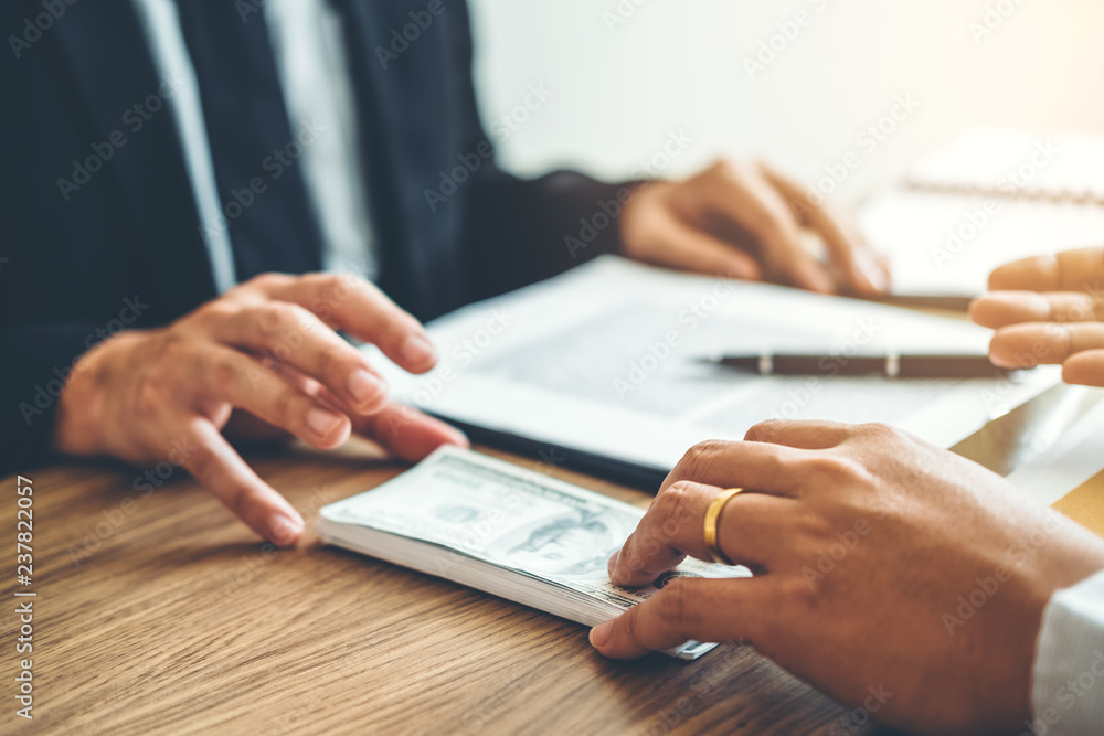 Corruption concept,Business man passing money dollar bills corruption bribery to businessman manager Corruption concept,Business man passing money dollar bills corruption bribery to businessman manager