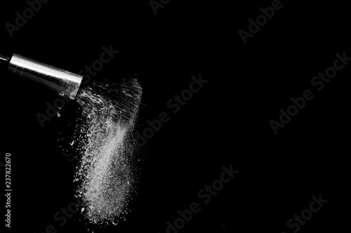 white powder splash and brush for makeup artist or beauty blogger in black background © pariwatpannium