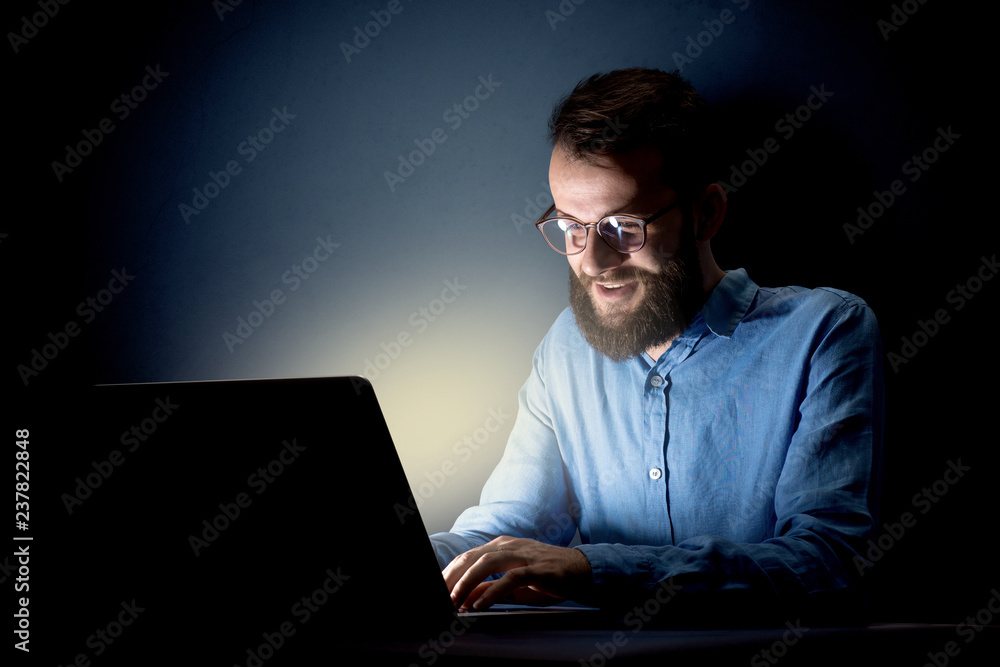 Young handsome businessman working late at night in the office with a dark background Young handsome businessman working late at night in the office with a dark background