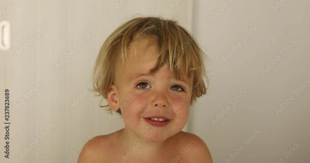 Adorable happy baby boy looks around and then smiles and laughs. 2 year old fair-haired child smiles at home Adorable happy baby boy looks around and then smiles and laughs. 2 year old fair-haired child smiles at home
