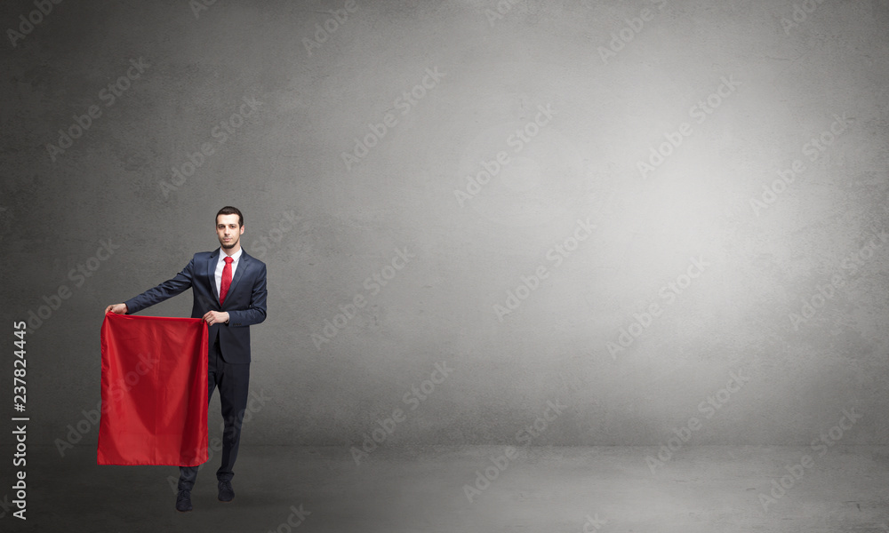 Businessman standing with red toreador cloth in his hand in an empty room
Businessman standing with red toreador cloth in his hand in an empty room