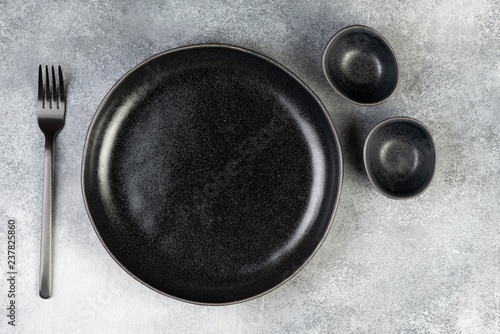 Obraz na płótnie Empty black plate, fork, knife, spoon on blue background, top view w salonie