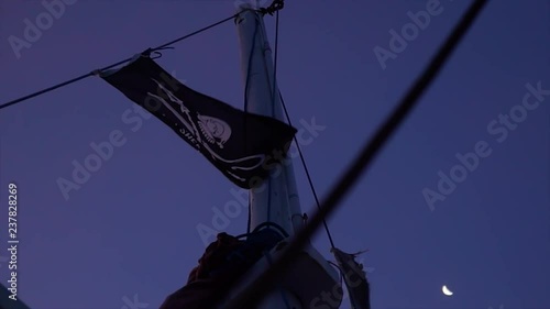 a pirate flag in slow motion is waving in the vind with the moon in the background photo