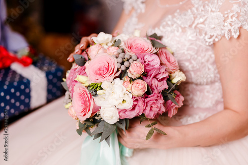 large round bouquet of the bride in women's hands. The bride holds a bouquet