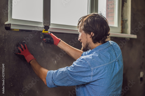 Man in a blue shirt does window installation