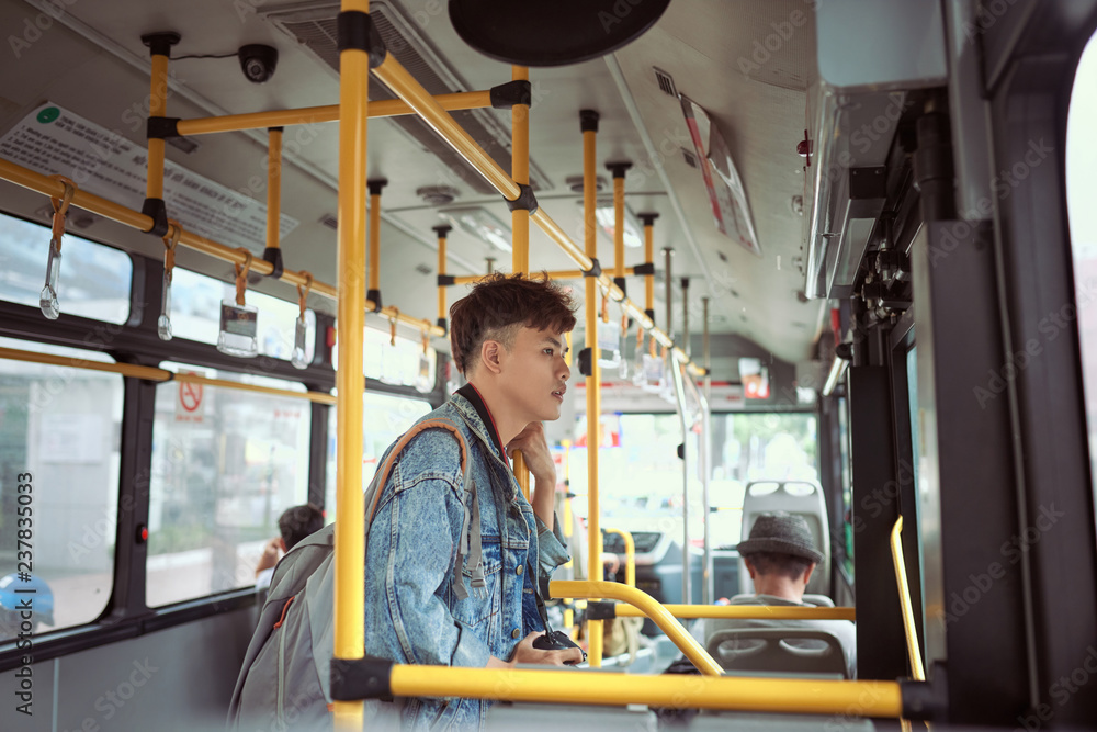 Fototapeta premium People, lifestyle, travel and public transport. Asian man standing inside city bus.