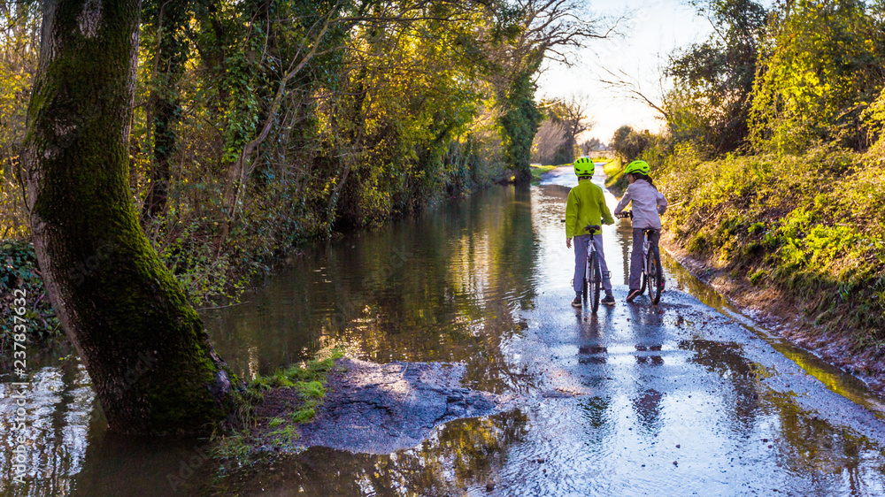 enfants à vélo sur route inondée