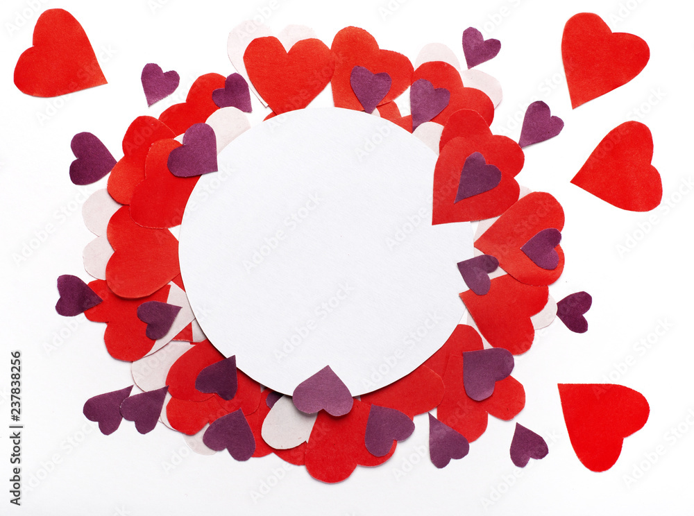 Creative layout made of colored paper hearts and a circular scrap of paper placed in the center. Valentine with place for text. Celebration concept.