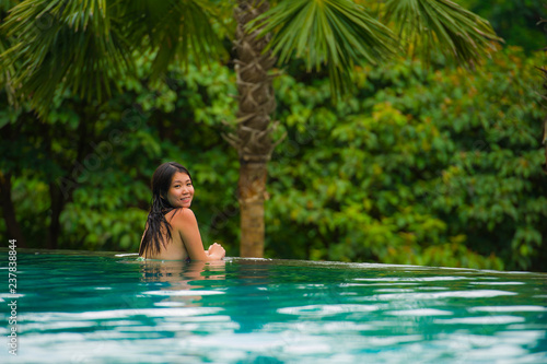young attractive and beautiful Asian Chinese woman relaxing happy at tropical beach resort swimming at jungle infinity pool enjoying Summer holidays in paradise island © TheVisualsYouNeed