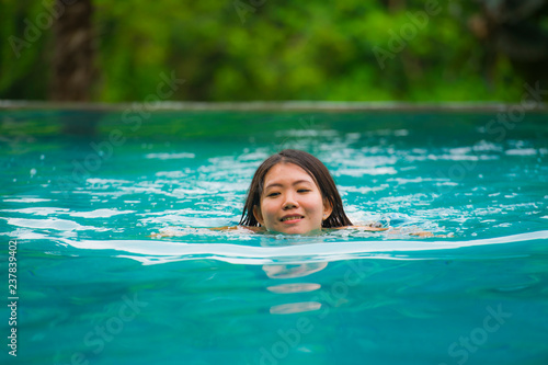 young attractive and beautiful Asian Korean woman relaxing happy at tropical beach resort swimming at hotel pool enjoying Summer holidays in paradise island © TheVisualsYouNeed