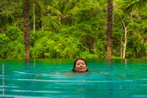 young attractive and beautiful Asian Korean woman relaxing happy at tropical beach resort swimming at hotel pool enjoying Summer holidays in paradise island