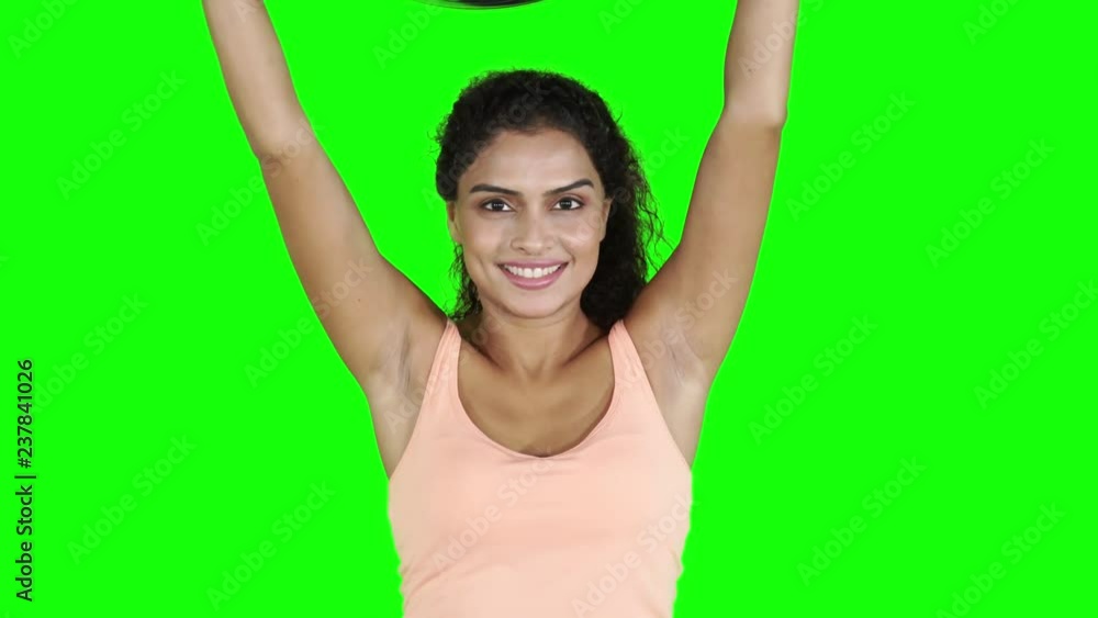 Happy young woman doing workout with a pilates ball and smiling at the camera. Shot in 4k resolution with green screen background Happy young woman doing workout with a pilates ball and smiling at the camera. Shot in 4k resolution with green screen background
