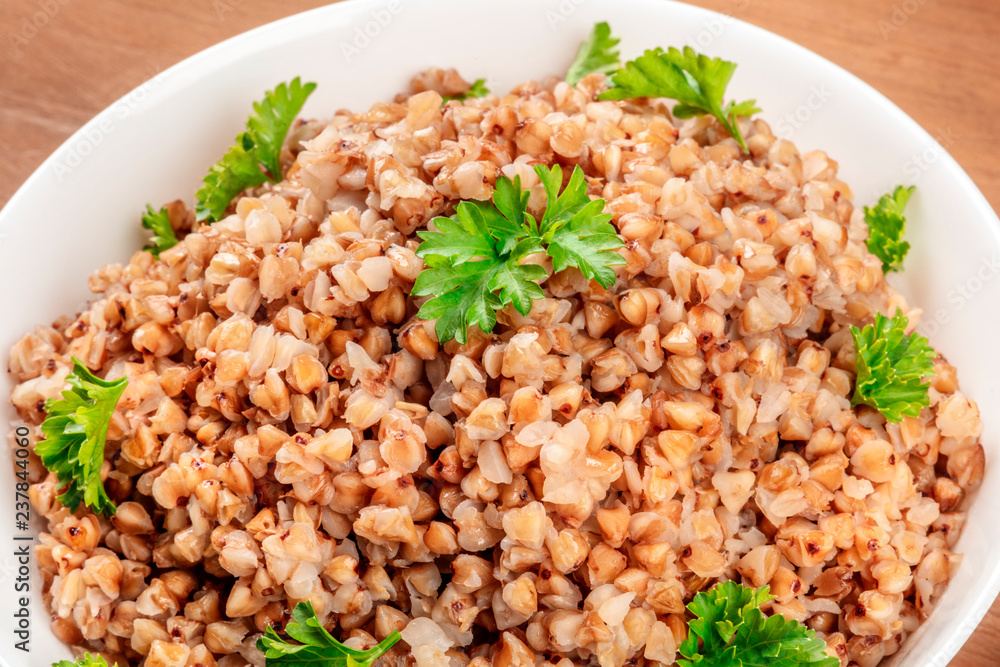 A closeup photo of boiled buckwheat in a bowl, garnished with fresh parsley A closeup photo of boiled buckwheat in a bowl, garnished with fresh parsley