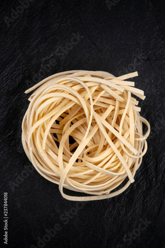 A photo of udon noodles in the shape of a nest, shot from above on a dark background with copy space