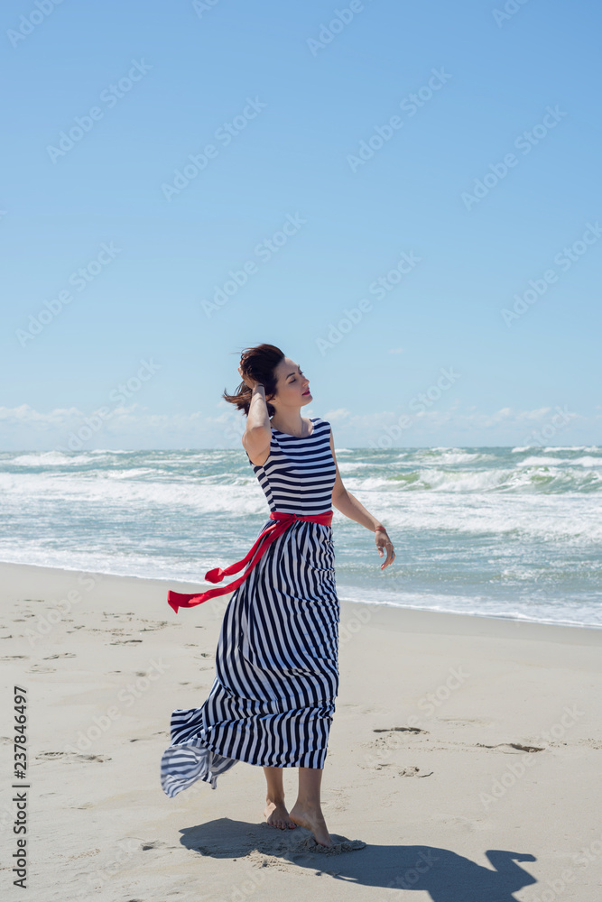 Beautiful brunette woman in a long dress walks along the seashore Beautiful brunette woman in a long dress walks along the seashore