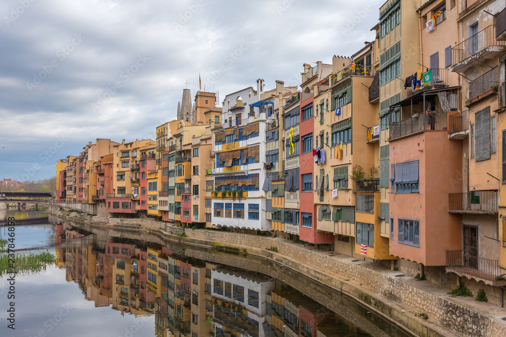 Colorful yellow, red and orange houses with the Catalan flags reflected in water river Onyar, in Girona, Catalonia, Spain.