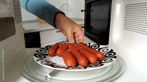 Woman Warms Sausages Iin The Mmicrowave	 photo