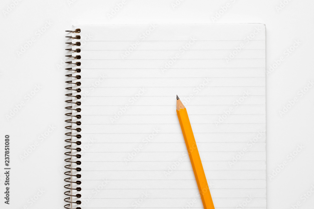 Yellow pencil on a lined notepad on a spiral on a white background Yellow pencil on a lined notepad on a spiral on a white background