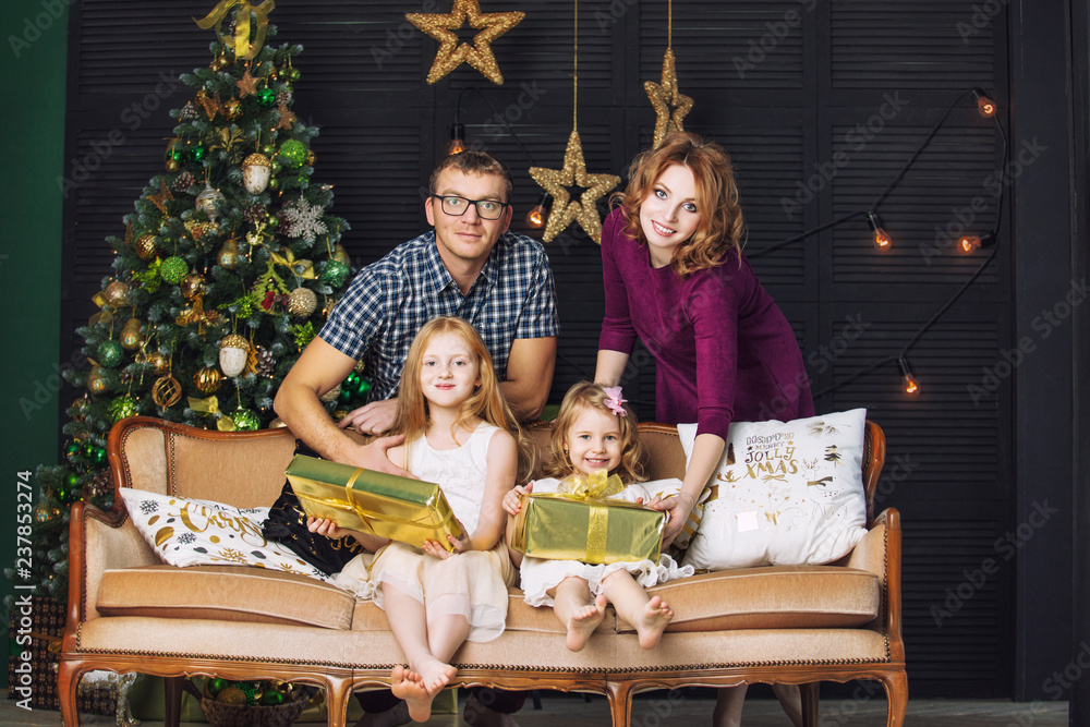 Family mom, dad and kids little girls with gifts together happy trendy beautiful in Christmas interior home