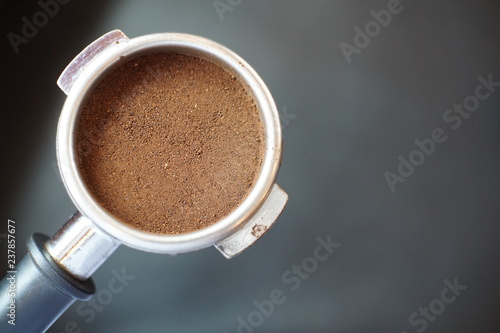 Portafilter with ground coffee on black background with copy space, top view