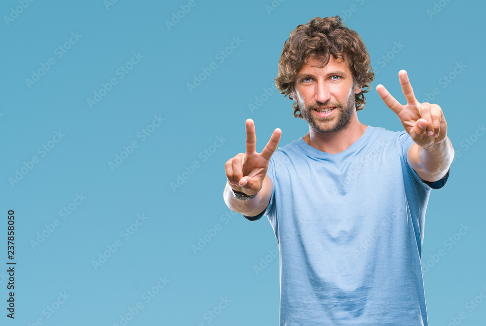 Handsome hispanic model man over isolated background smiling with happy face winking at the camera doing victory sign. Number two. Handsome hispanic model man over isolated background smiling with happy face winking at the camera doing victory sign. Number two.