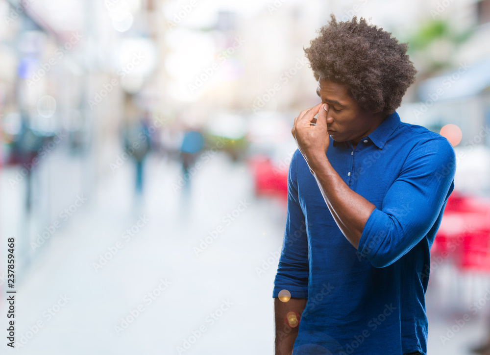 Afro american man over isolated background tired rubbing nose and eyes feeling fatigue and headache. Stress and frustration concept.