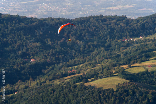 Paragliding at stunning mountain scenery with green pastures and forests © Petar