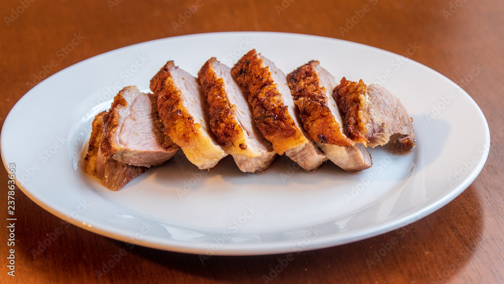 Seared duck breast with crispy skin on a white ceramic plate 
