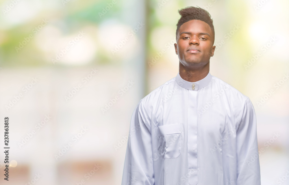 Young arabic african man wearing traditional djellaba over isolated background with serious expression on face. Simple and natural looking at the camera. Young arabic african man wearing traditional djellaba over isolated background with serious expression on face. Simple and natural looking at the camera.