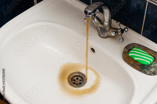 Canvas-taulu Dirty rusty water flows into a white sink