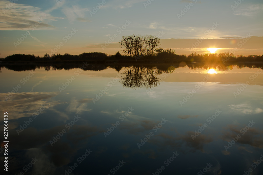 Sunrise over the lake and reflection of clouds in the water