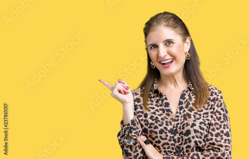 Beautiful middle age mature rich woman wearing leopard dress over isolated background with a big smile on face, pointing with hand and finger to the side looking at the camera.