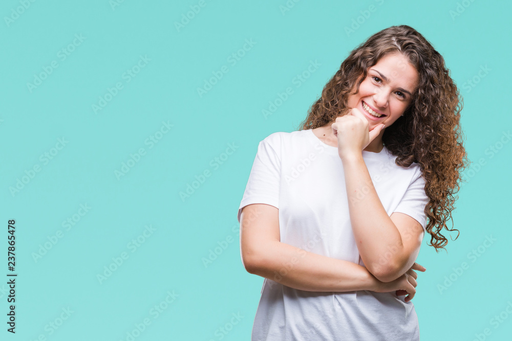 Beautiful brunette curly hair young girl wearing casual t-shirt over isolated background looking confident at the camera with smile with crossed arms and hand raised on chin. Thinking positive.